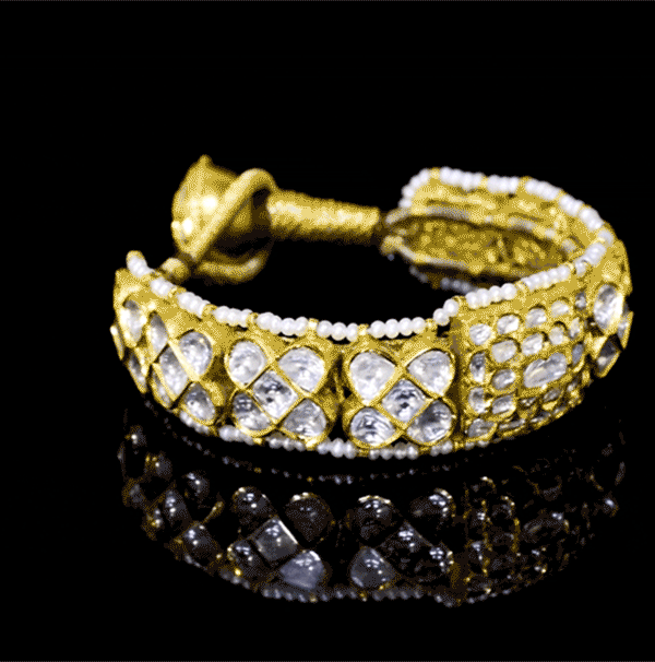 Luxurious handcrafted gold Pounchi Bangle adorned with intricate polki diamond floral motifs and bordered with delicate pearls. A perfect blend of traditional artistry and royal elegance.(KMB0581)