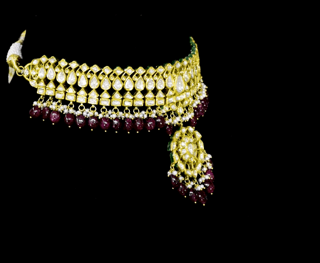 This white choker necklace and jhoomki pair is beautifully crafted with uncut diamonds, and strung with rubies and pearls. A perfect blend of elegance and tradition for weddings and festive occasions.(KMNE3585)