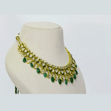 An elegant necklace and earring set featuring diamond polki framed by a vivid green circle, strung with emerald maniya and pearls. Blending heritage craftsmanship with refined luxury, it’s perfect for graceful, modern celebrations. (KMNE3588)