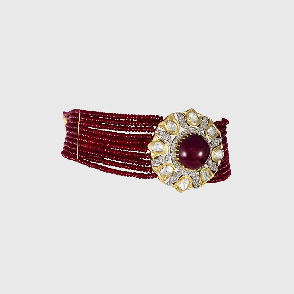 This exquisite piece features a central ruby cabochon surrounded by uncut and round diamonds in a floral design, beautifully strung with ruby beads on both sides. A perfect blend of grace and grandeur.(KMNE3603)