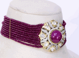 This exquisite piece features a central ruby cabochon surrounded by uncut and round diamonds in a floral design, beautifully strung with ruby beads on both sides. A perfect blend of grace and grandeur.(KMNE3603)