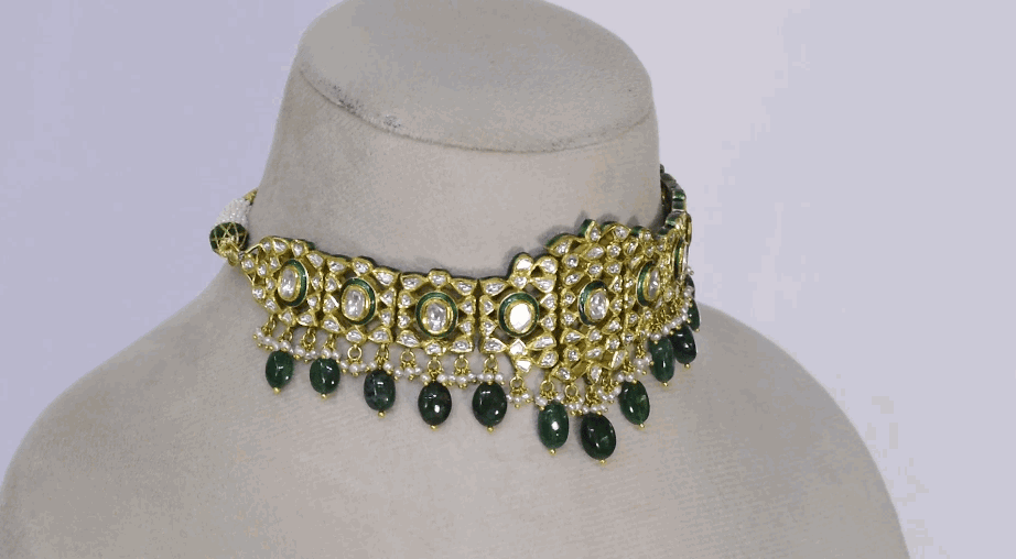 Embrace timeless elegance with this green Meena choker necklace and tops set, featuring sparkling uncut diamond polki, strung with vibrant emerald maniya and delicate pearls. Perfect for adding royal charm to any festive or bridal look.(KMNE3604)