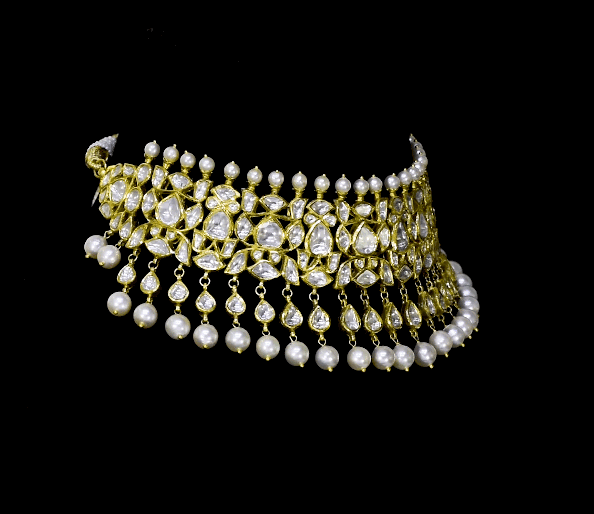 Elevate your style with this stunning semi-choker necklace and earring pair, featuring dazzling uncut diamond polki and a striking larger center stone, beautifully strung with pearls. Perfect for adding royal charm to any special occasion.(KMNE3611)