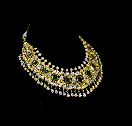 Make a majestic statement with this grand necklace set, featuring uncut diamond Polki, a striking emerald centerpiece, rich red stones, and delicate pearls in the funghar. A masterpiece of regal elegance.(KMNE3616)