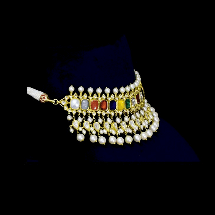 A vibrant Navratan choker in gold, adorned with polki diamonds and nine gemstones, finished with cascading pearl fringes, paired with statement earrings for a rich, traditional, and festive look. (KMNE3705)