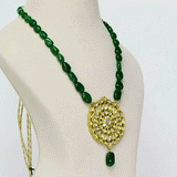 A traditional pendant adorned with hand-set polki diamonds, featuring intricate detailing and timeless elegance. Finished with rich emerald maniya stringing, it celebrates heritage craftsmanship with a touch of regal charm. (KMPE1325)