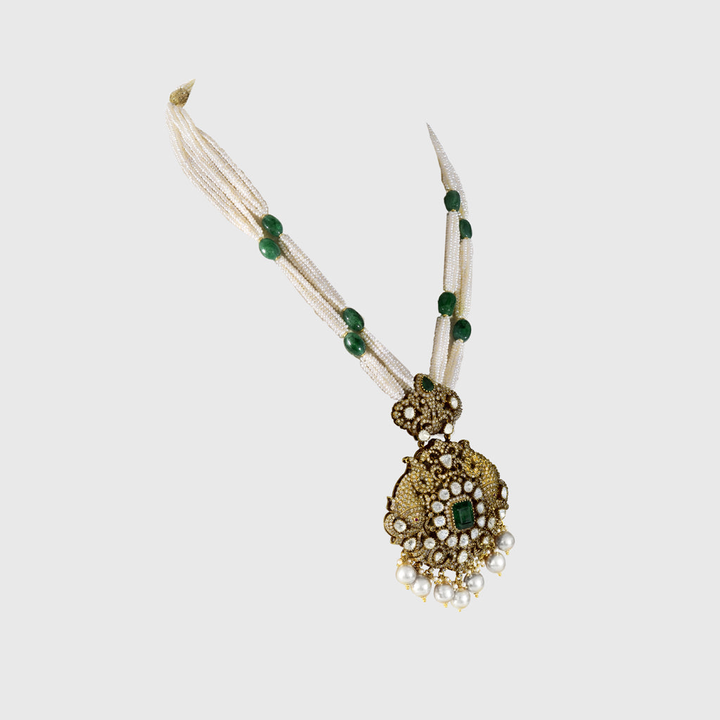 Discover refined elegance with this fusion-style pendant, showcasing uncut diamond Polki, round diamonds, and a central emerald. Strung with pearls and long emerald beads, it’s a striking blend of tradition and modern sophistication.(KMPE1327)