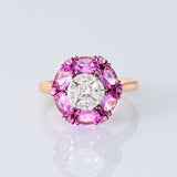 A radiant round diamond embraced by a halo of vivid pink sapphires—where timeless brilliance meets feminine charm. (PGDR0524)