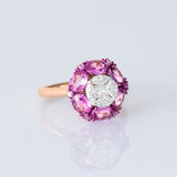 A radiant round diamond embraced by a halo of vivid pink sapphires—where timeless brilliance meets feminine charm. (PGDR0524)