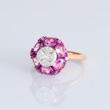 A radiant round diamond embraced by a halo of vivid pink sapphires—where timeless brilliance meets feminine charm. (PGDR0524)